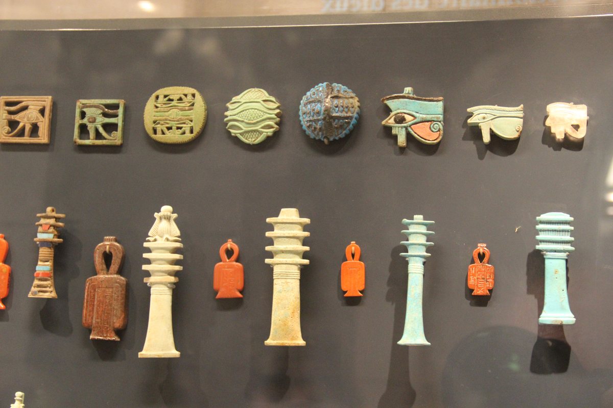 Colourful ancient Egyptian faience amulets arranged in a museum case