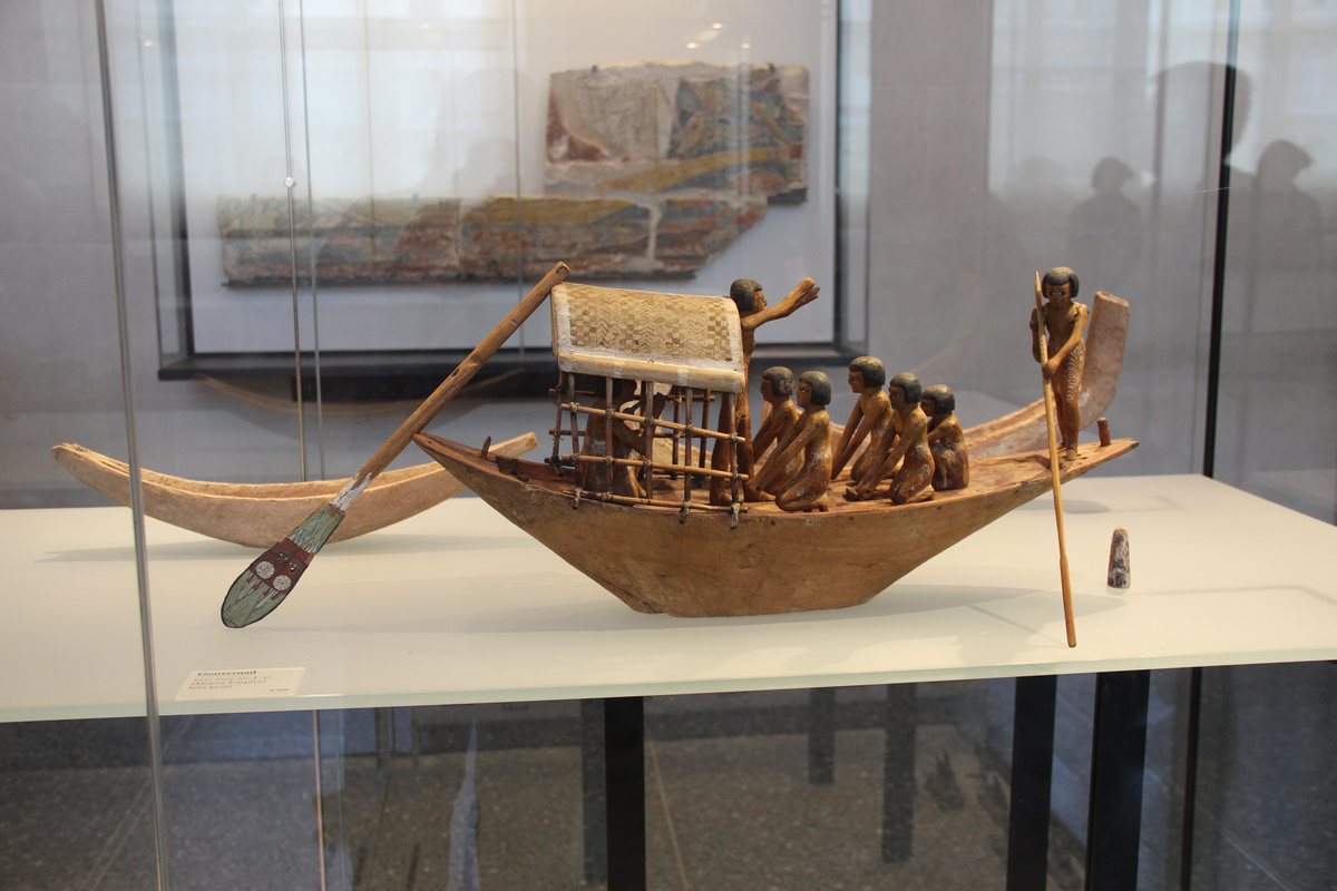 Ancient Egyptian wooden boat model displayed in a museum case